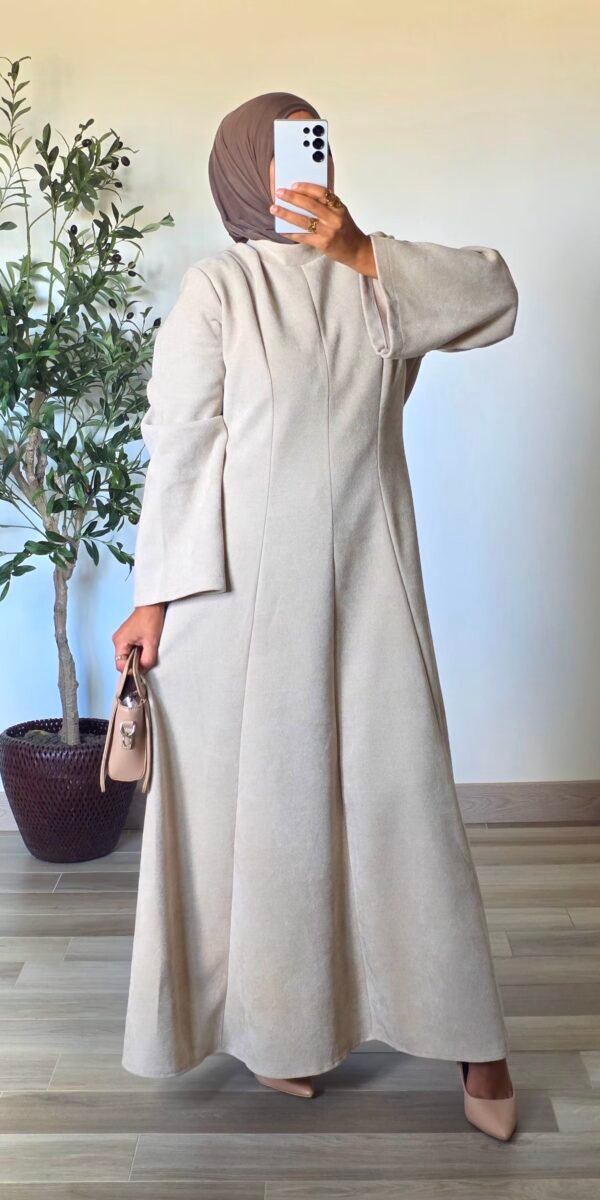 Femme portant une robe longue en velours crème, coupe évasée et manches amples