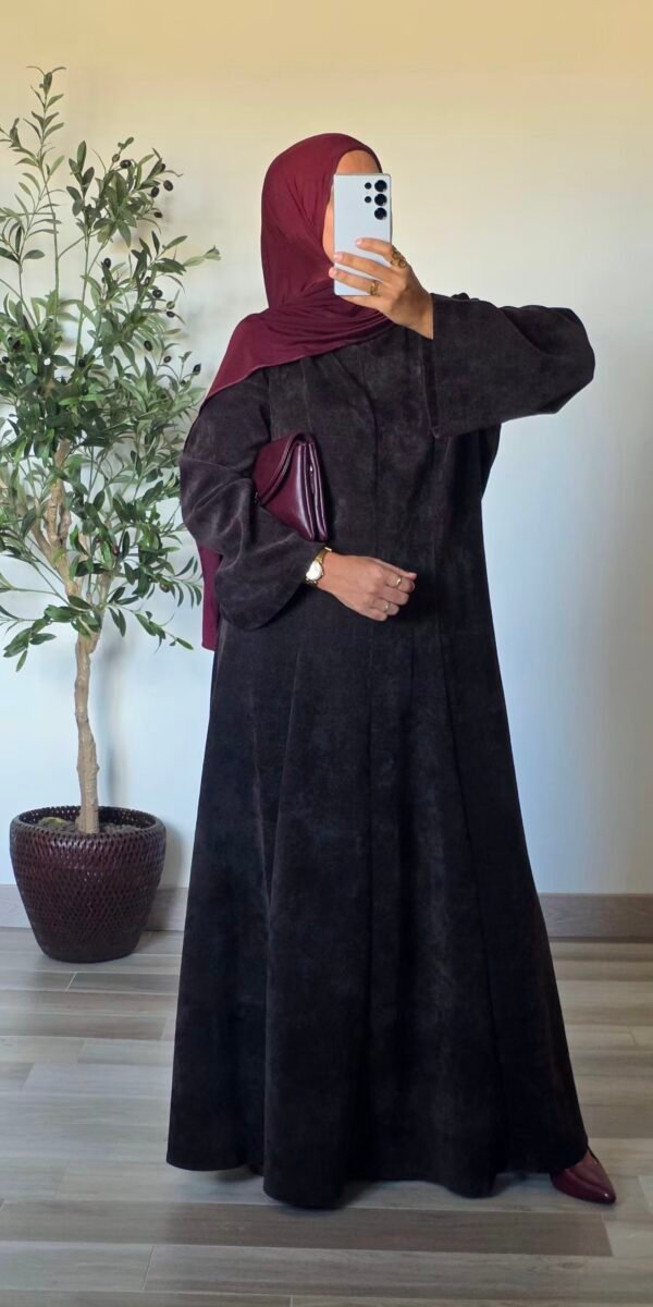 Femme portant une robe longue en velours marron, coupe évasée et manches amples
