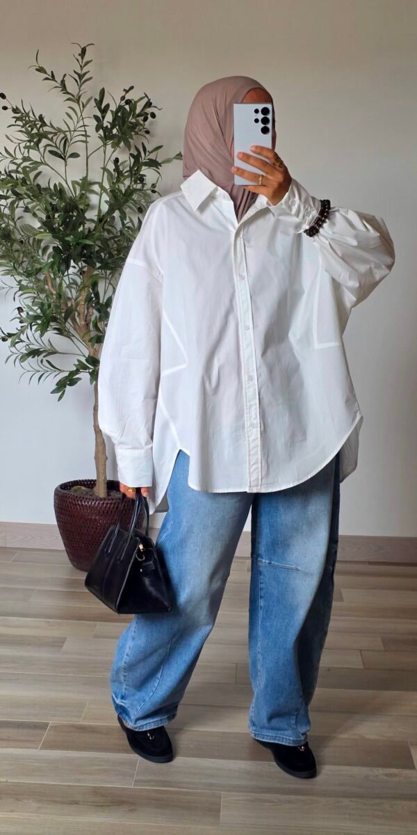 Femme portant une chemise longue oversize blanche en coton avec une jupe longue noire