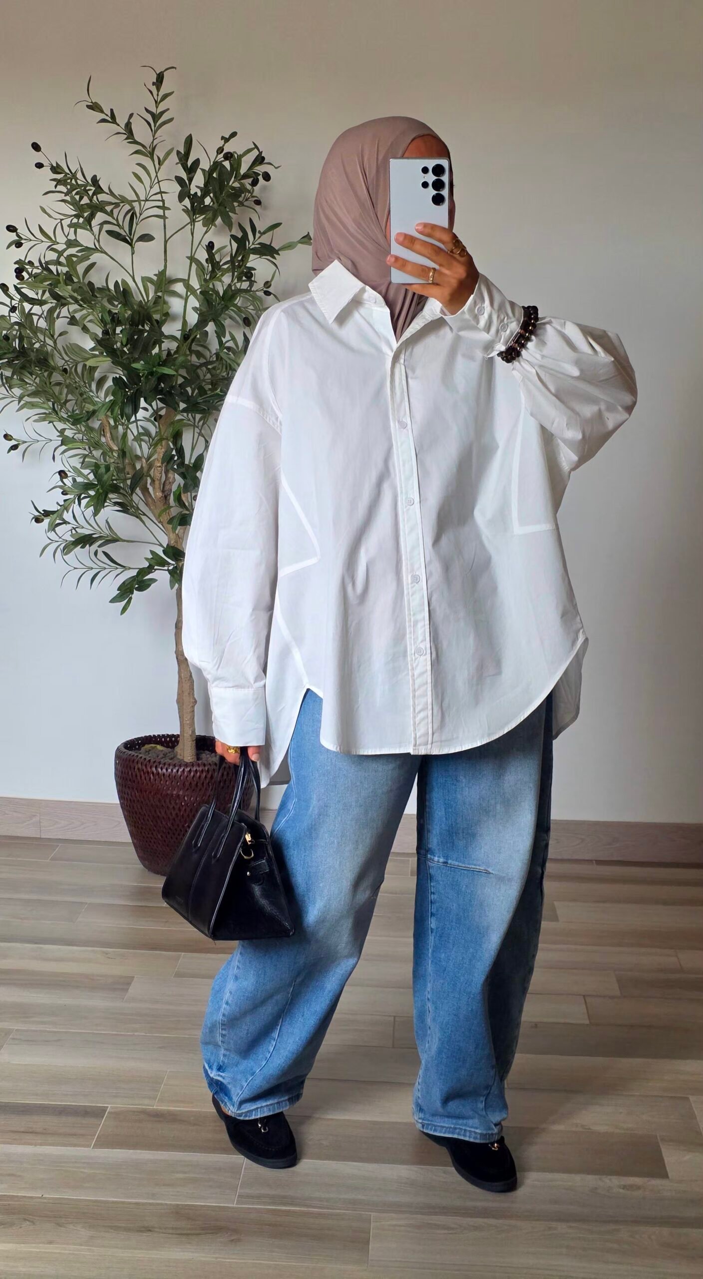 Femme portant une chemise longue oversize blanche en coton avec une jupe longue noire