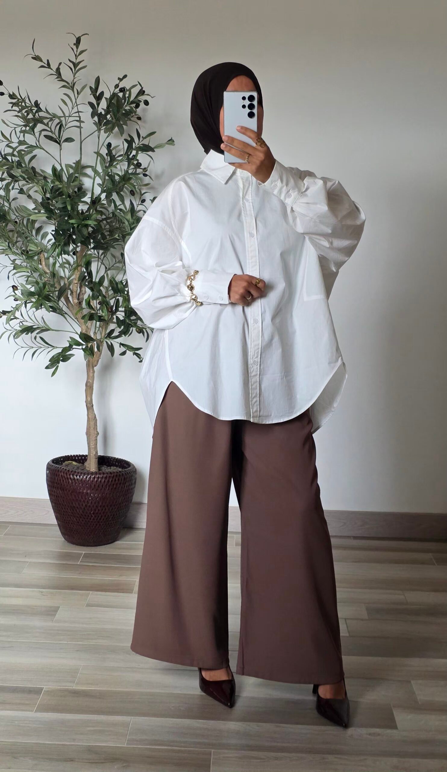 Femme portant une chemise longue oversize blanche en coton avec une jupe longue noire
