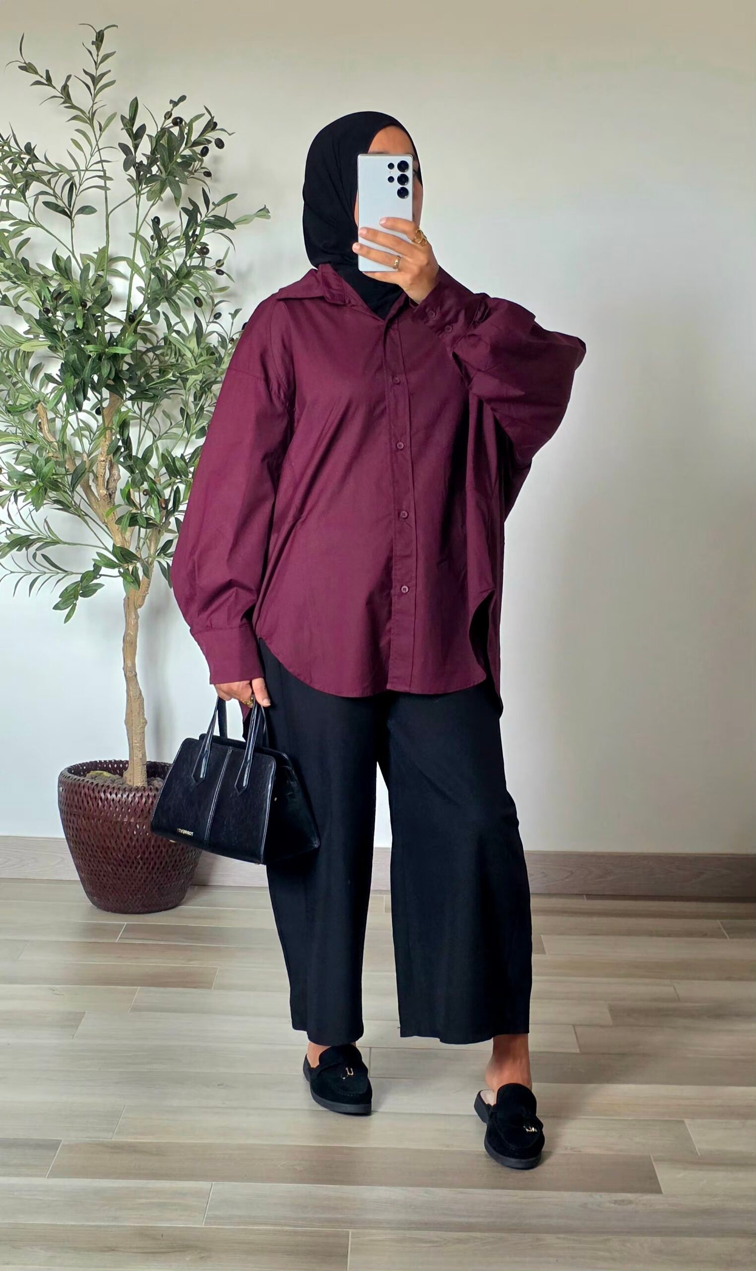 Femme portant une chemise longue oversize bordeaux en coton avec une jupe longue noire