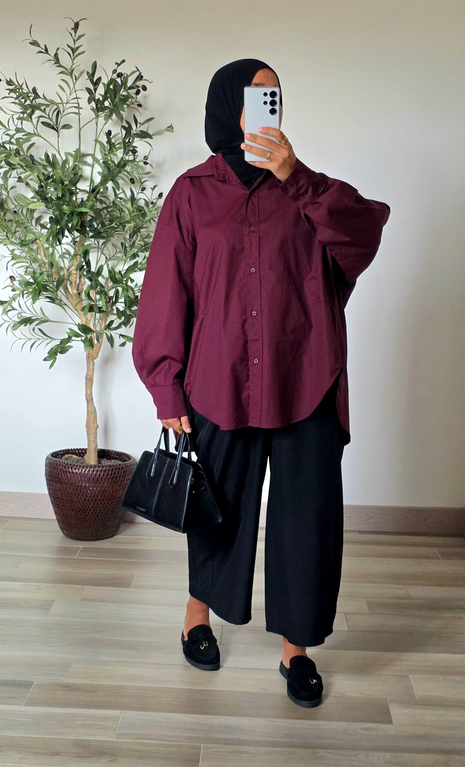 Femme portant une chemise longue oversize bordeaux en coton avec une jupe longue noire