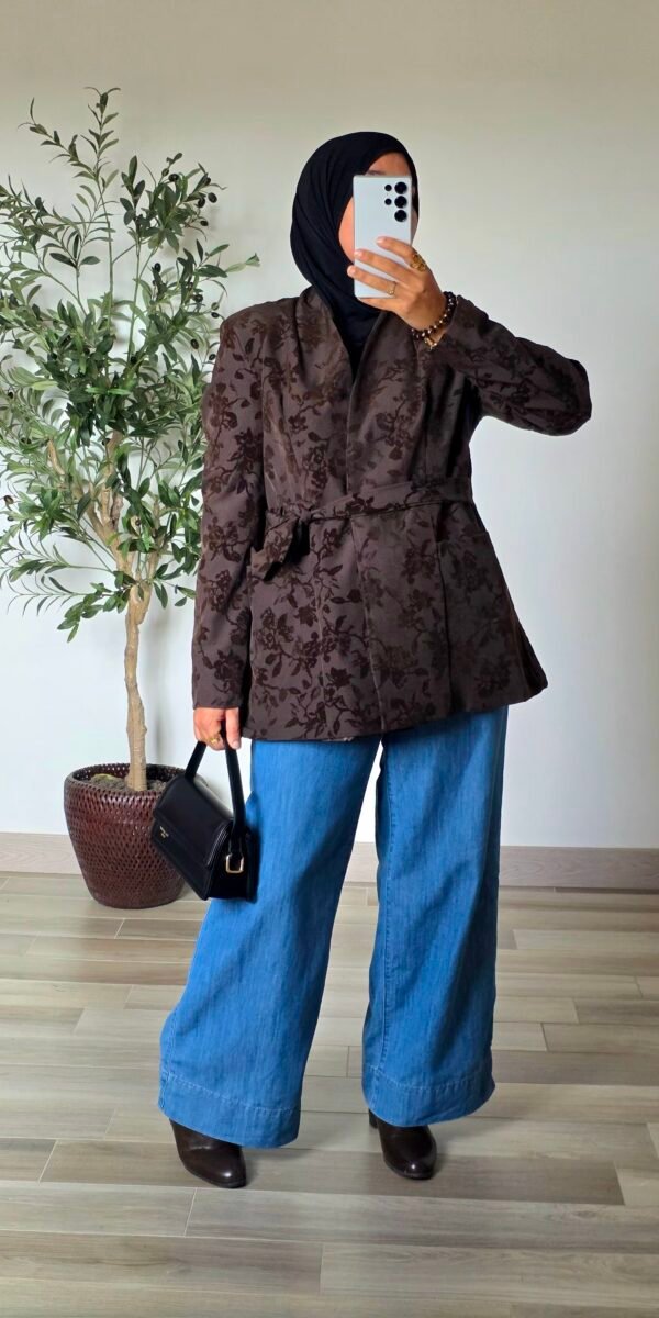Femme portant une veste jacquard taupe à motifs floraux avec un jean large