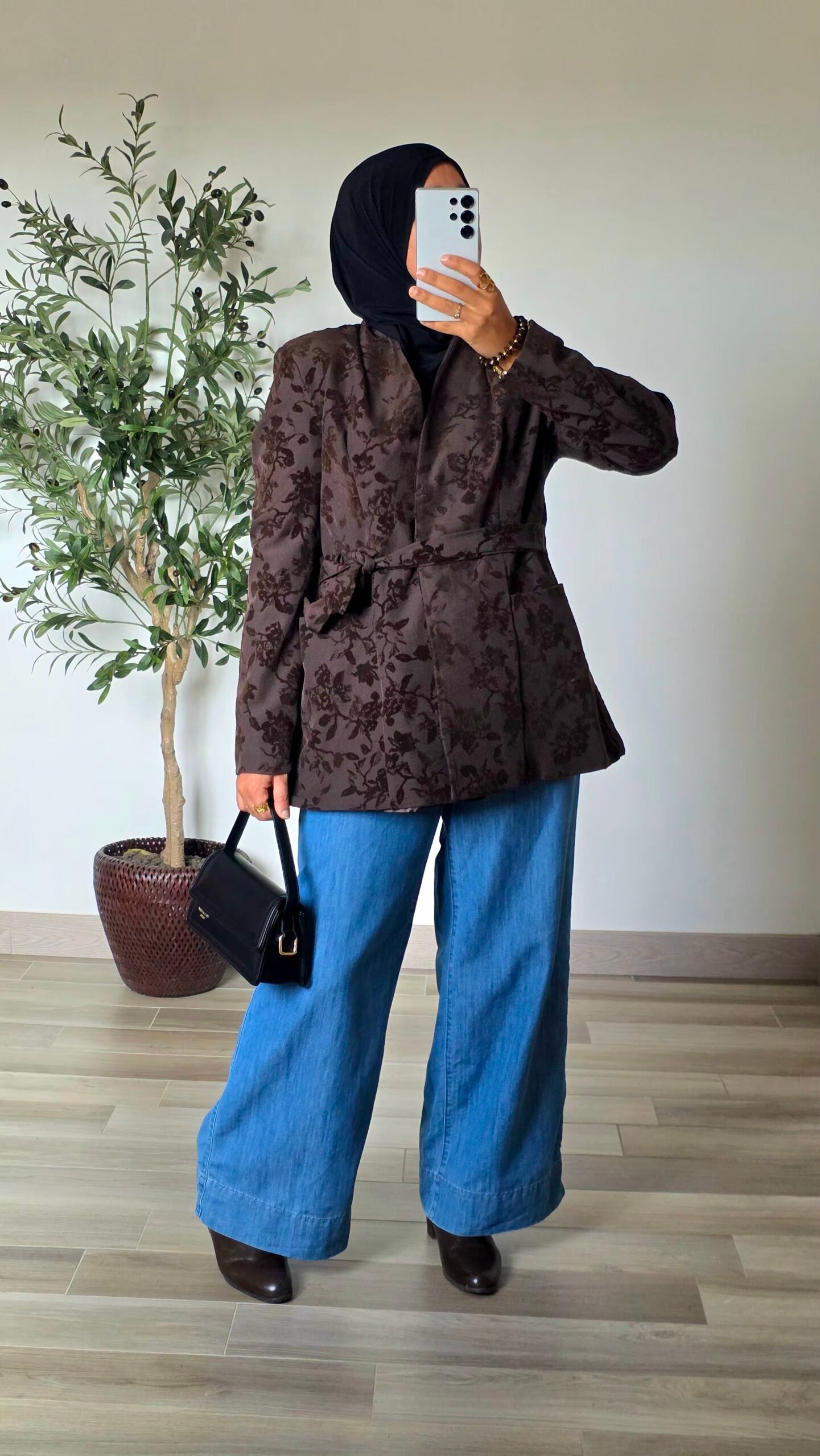 Femme portant une veste jacquard taupe à motifs floraux avec un jean large