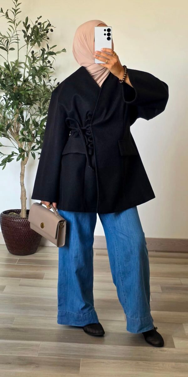 Femme portant une veste manteau noire effet laine avec fermeture à nouer