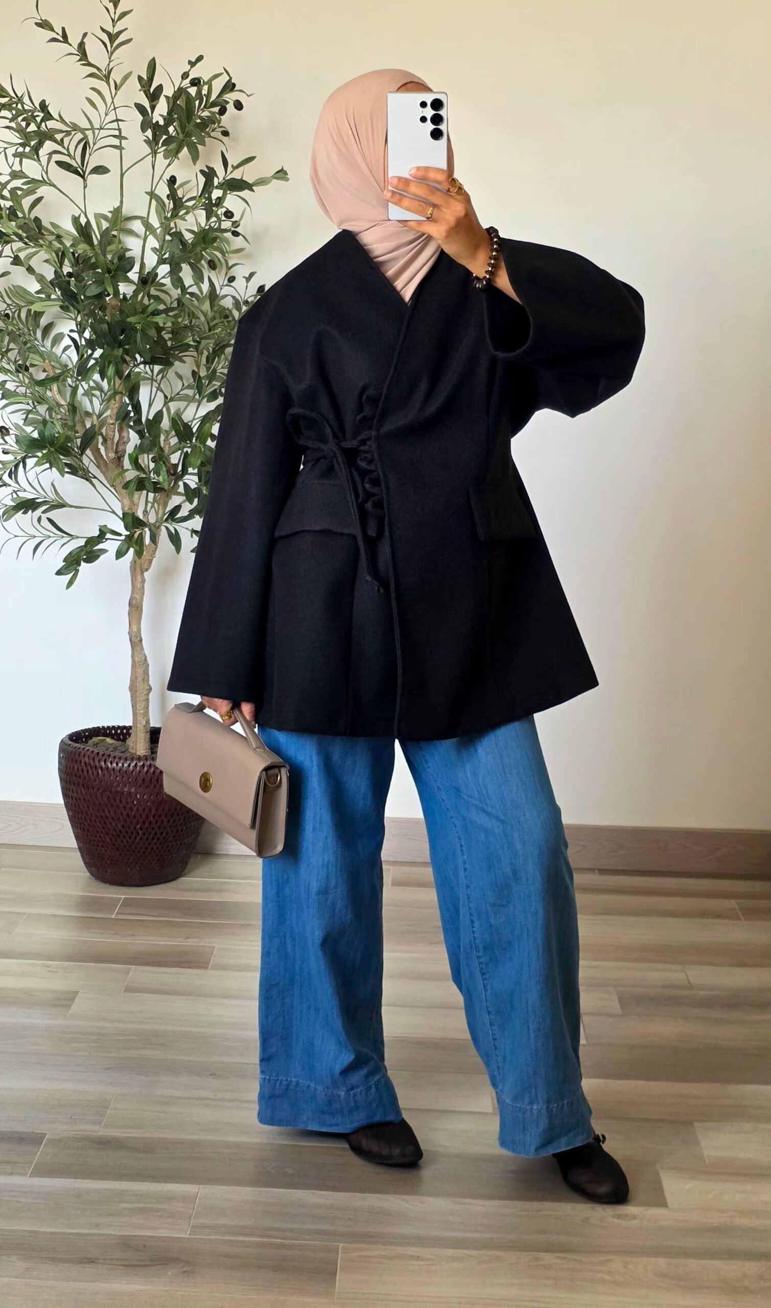 Femme portant une veste manteau noire effet laine avec fermeture à nouer