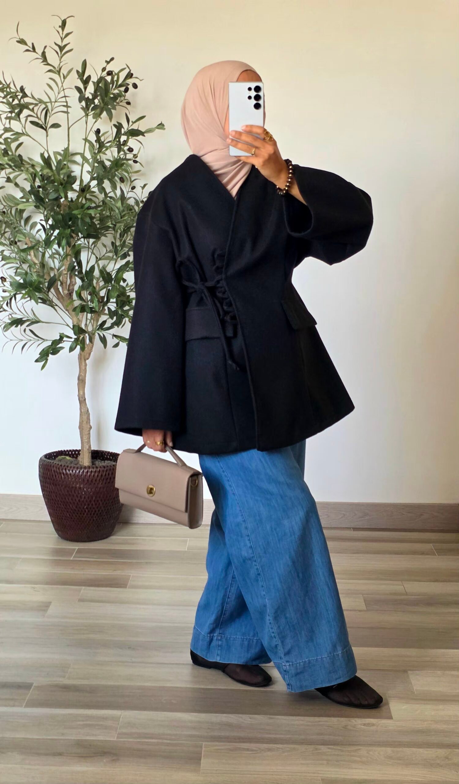Femme portant une veste manteau noire effet laine avec fermeture à nouer