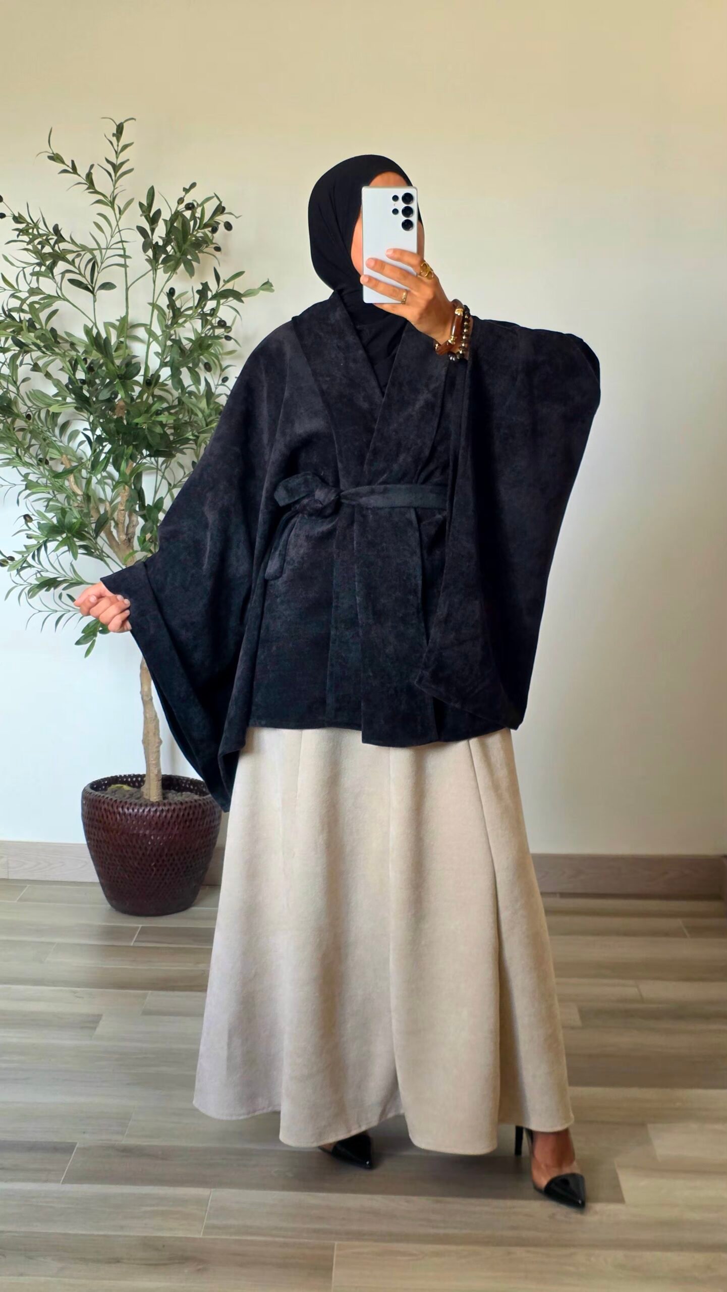 Femme portant un gilet cape en velours noir avec ceinture à nouer