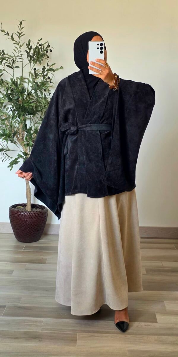 Femme portant un gilet cape en velours noir avec ceinture à nouer