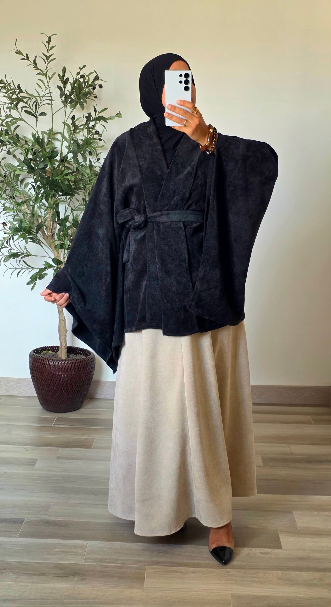 Femme portant un gilet cape en velours noir avec ceinture à nouer